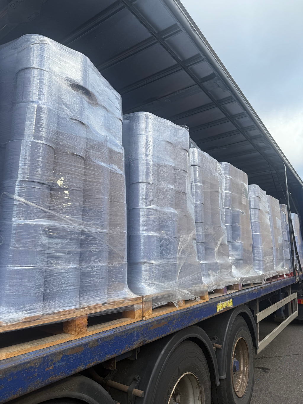 Pallets of blue centrefeed on a lorry outside a warehouse.