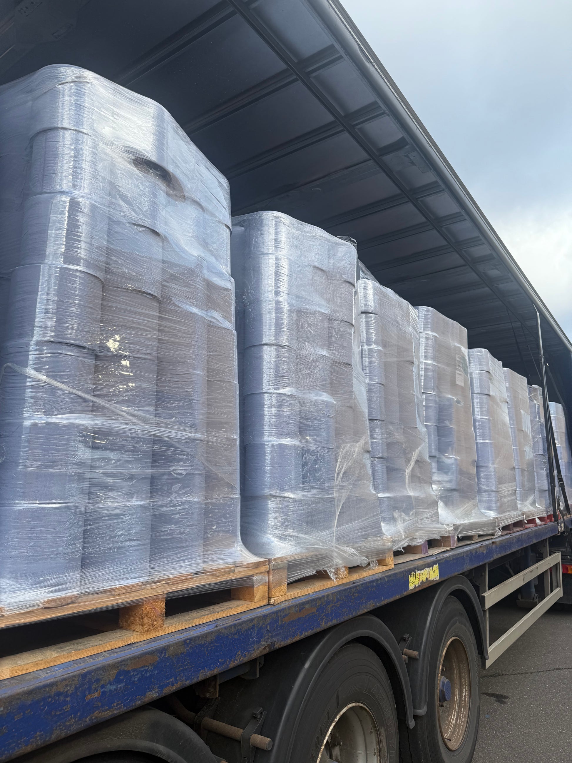 Pallets of blue centrefeed on a lorry outside a warehouse.