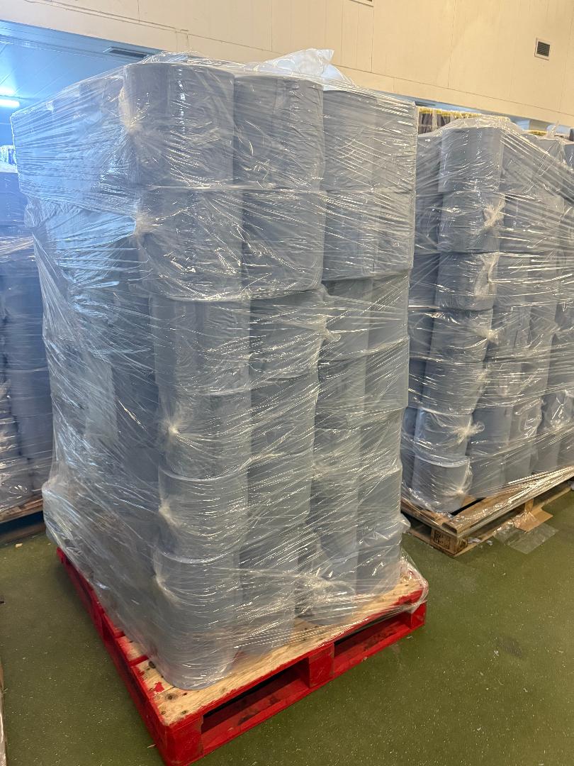 pallets of wrapped blue centrefeed rolls in a warehouse setting